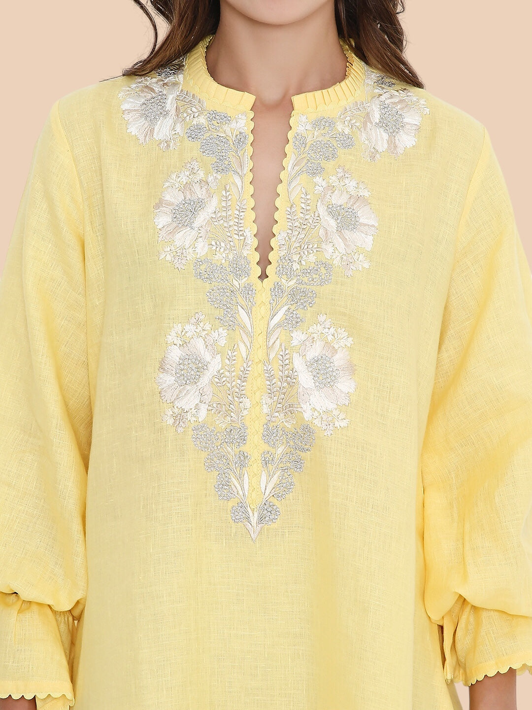 Yellow top with floral embroidery on a beige background