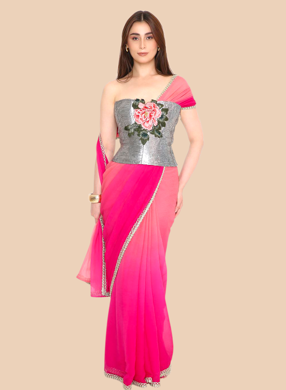 Woman wearing a pink corset with a silver blouse featuring floral embroidery on a beige background