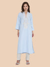 Woman wearing a light blue kurta with white embroidery on a beige background
