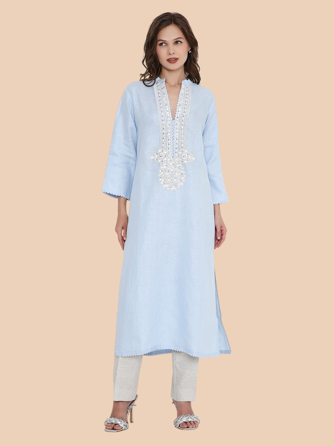 Woman wearing a light blue kurta with white embroidery on a beige background