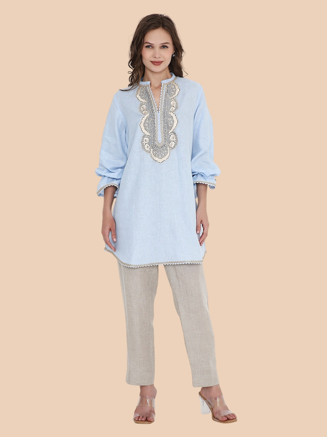 Woman wearing a light blue embroidered kurta with beige pants on a beige background