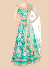 Teal embroidered lehenga with matching blouse and white dupatta on a beige background