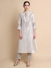 Woman wearing a white embroidered kurta with beige pants on a beige background