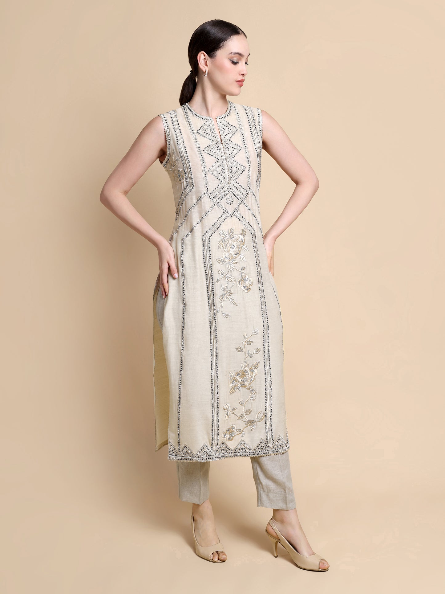 Woman wearing a sleeveless embroidered dress on a beige background