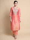 Woman wearing a peach kurta with floral embroidery on a beige background