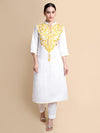 Woman wearing a white kurta with gold embroidery on a beige background