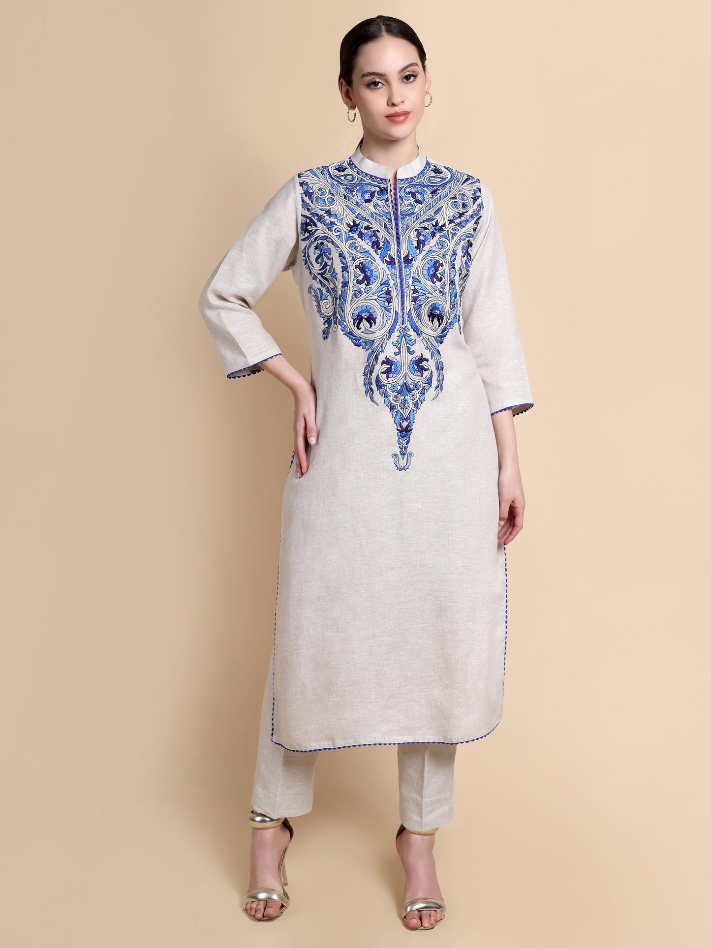 Woman wearing a white kurta with blue embroidery on a beige background