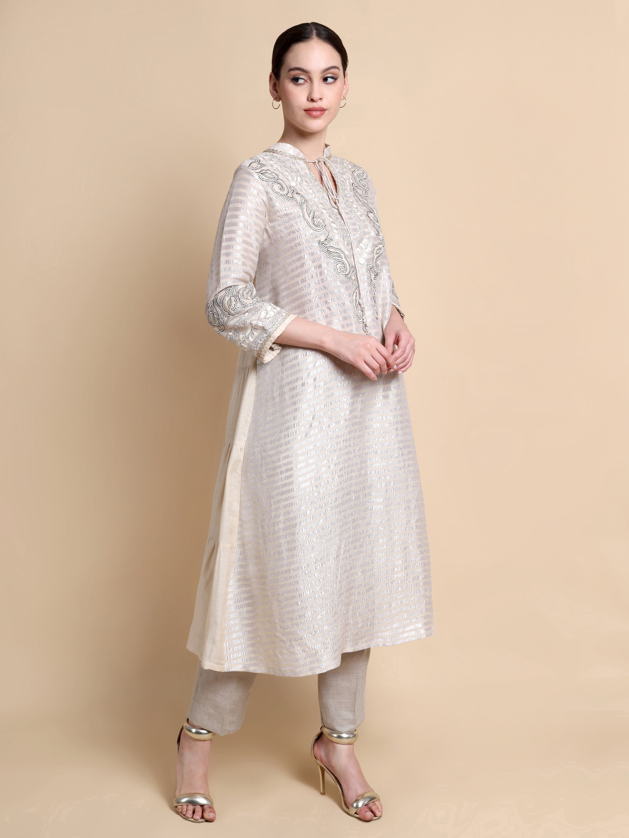 Woman wearing a white embroidered kurta with beige pants on a beige background