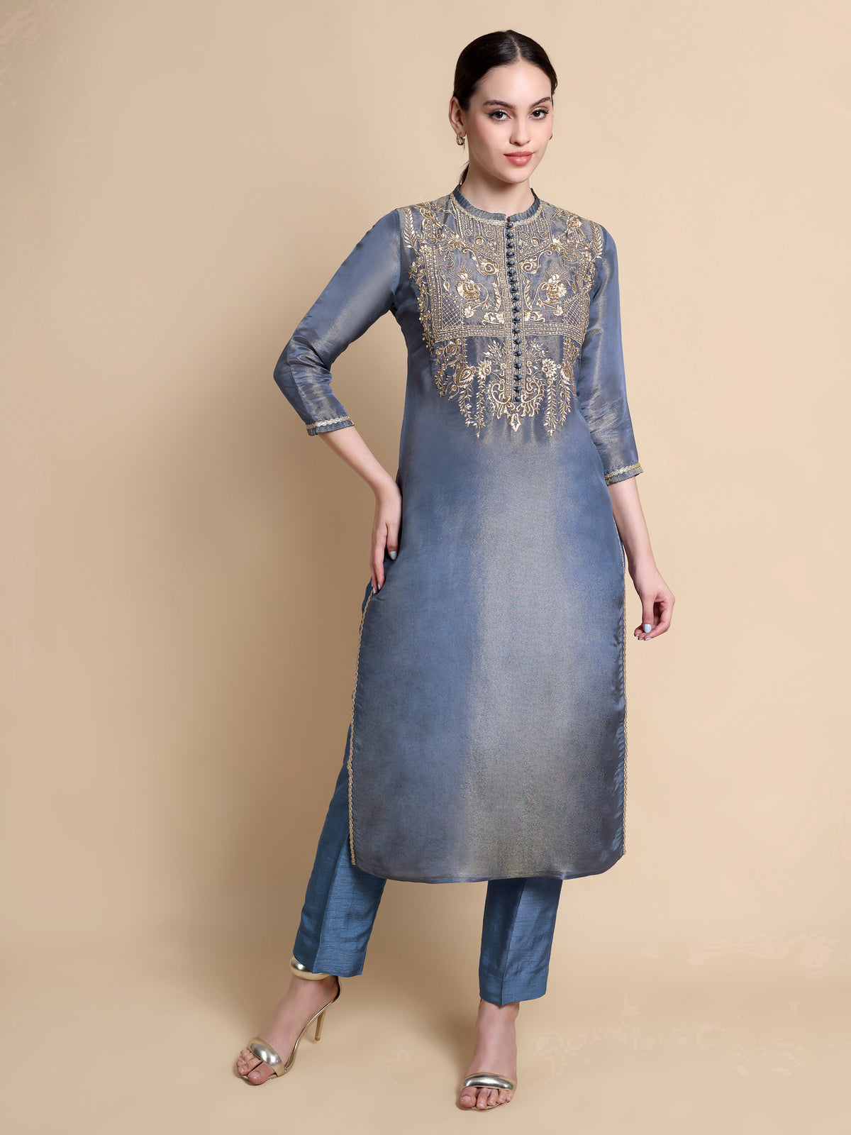Woman wearing a blue kurta with intricate embroidery on a beige background