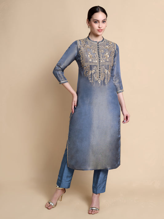 Woman wearing a blue kurta with intricate embroidery on a beige background