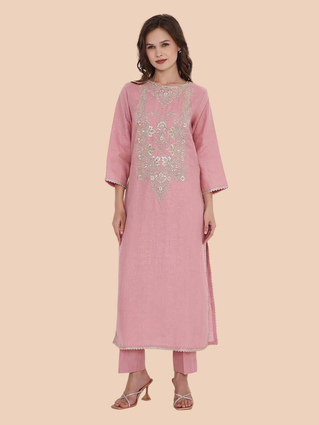 Woman wearing a pink traditional outfit with embroidery on a beige background