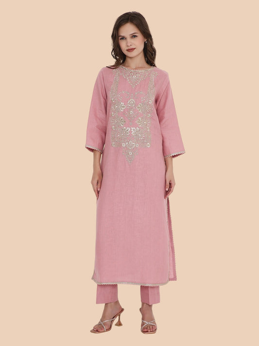 Woman wearing a pink traditional outfit with embroidery on a beige background