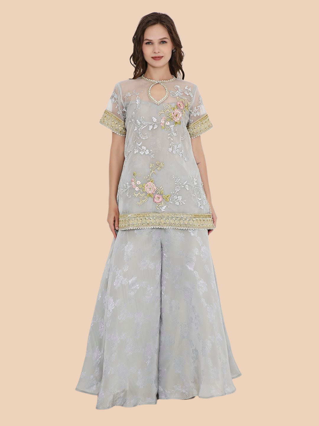 Woman wearing a light gray embroidered outfit on a beige background