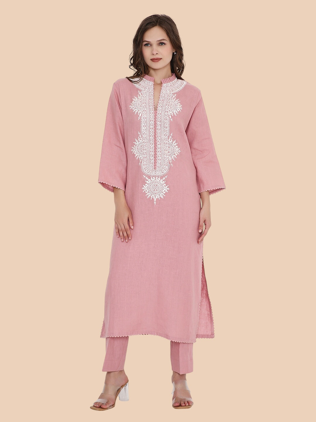 Woman wearing a pink kurta with white embroidery on a beige background