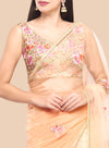 Woman wearing a peach saree with floral embroidery on a beige background