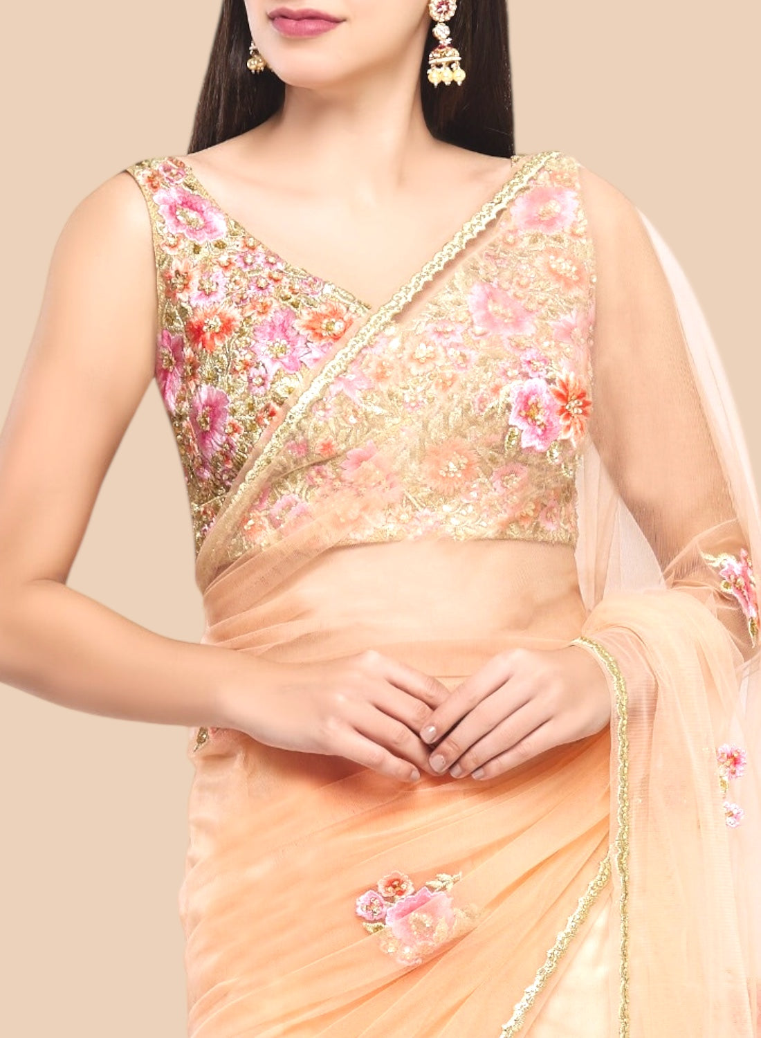 Woman wearing a peach saree with floral embroidery on a beige background