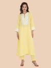 Woman wearing a light yellow kurta with lace details on a beige background