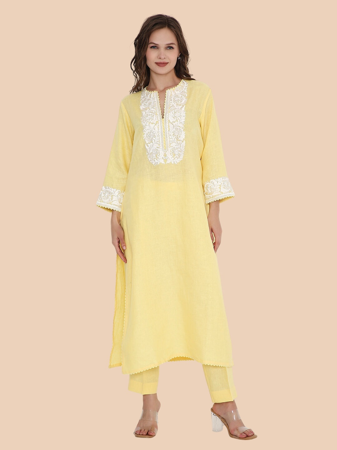 Woman wearing a light yellow kurta with lace details on a beige background