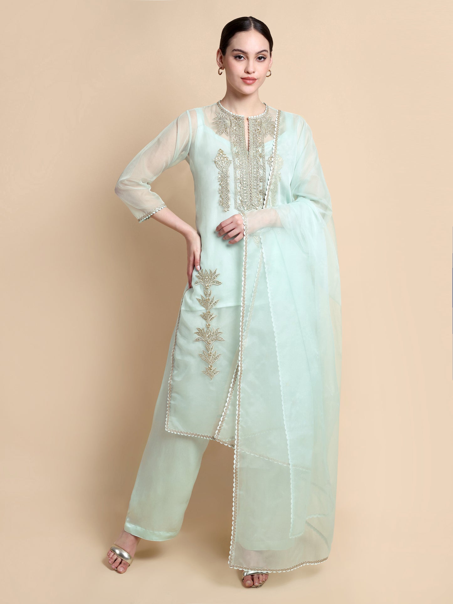 Woman wearing a light blue traditional outfit with embroidery on a beige background