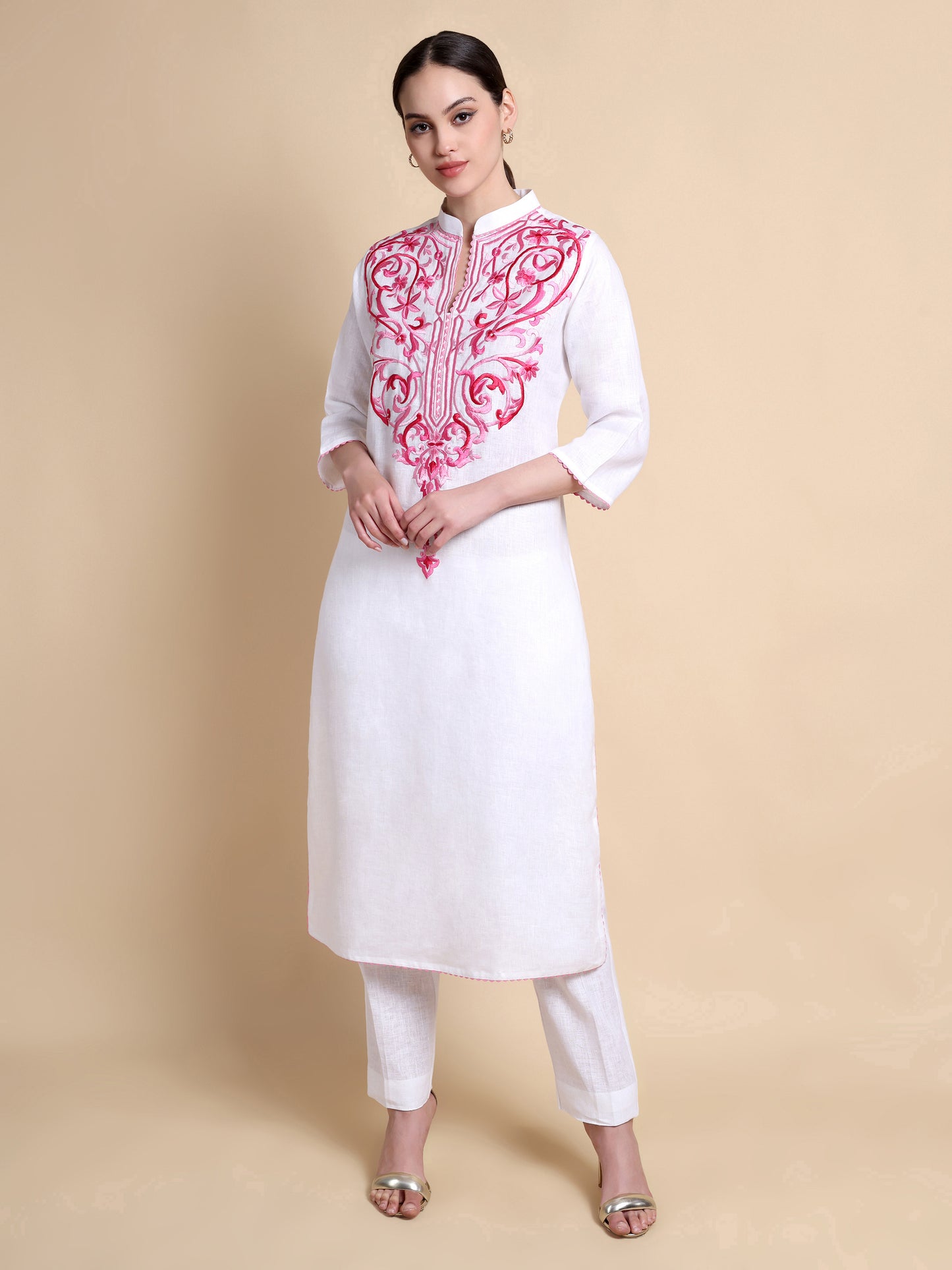 White kurta with pink embroidery on a beige background