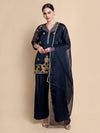 Woman wearing a navy blue traditional outfit with gold embroidery on a beige background