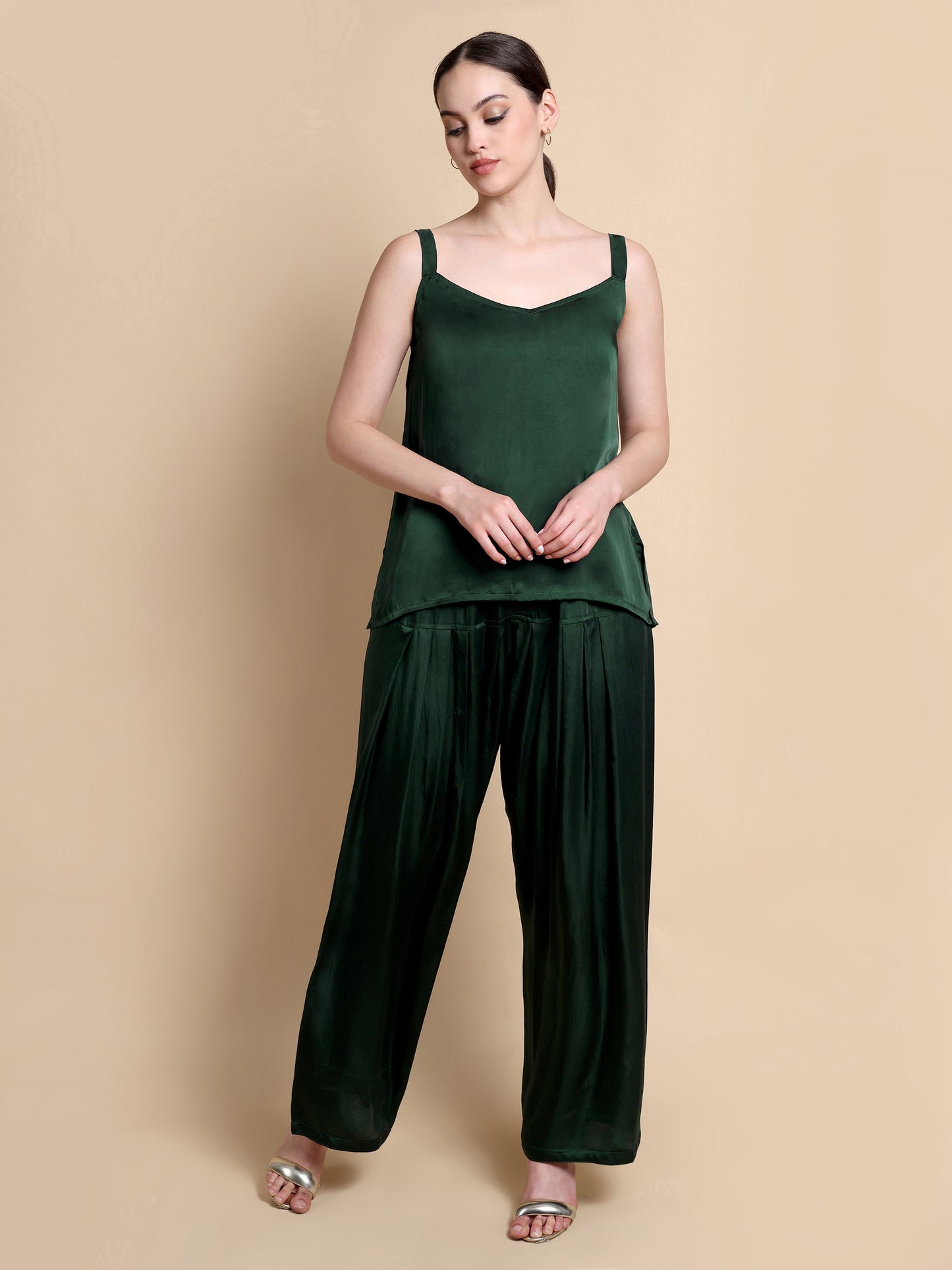 Woman wearing a green sleeveless top and wide-leg pants on a beige background