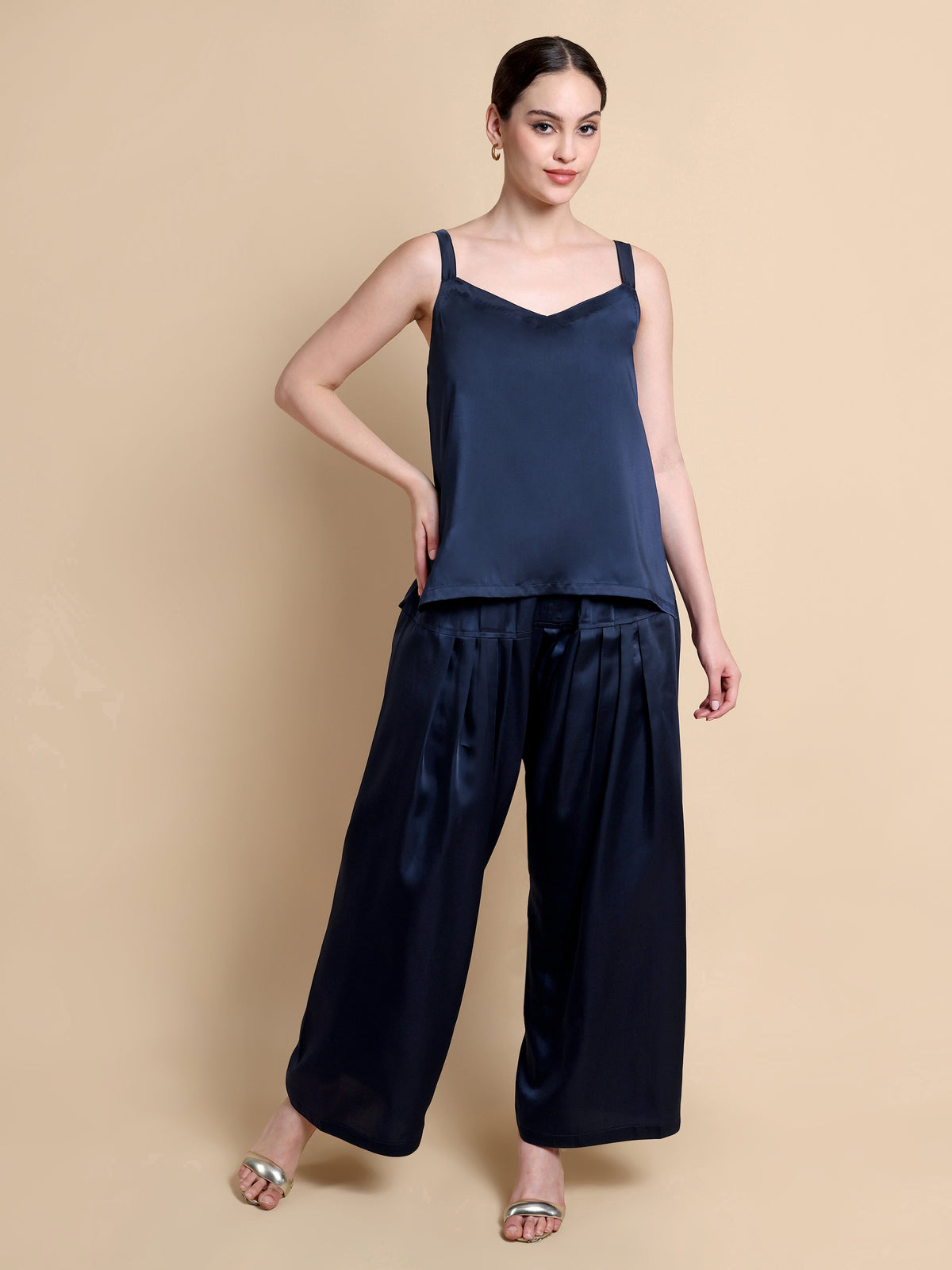 Woman wearing a navy blue sleeveless top and wide-leg pants on a beige background