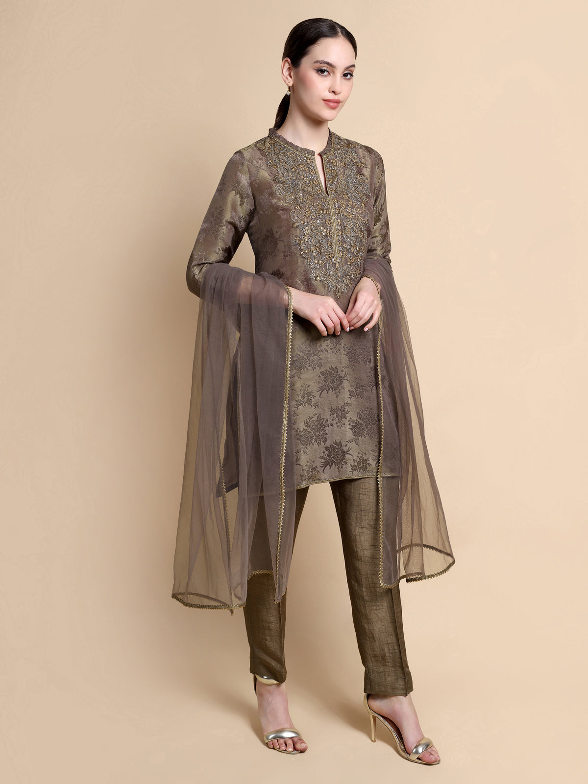 Woman wearing a traditional outfit with a brown and gold color scheme on a beige background