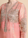 Pink embroidered garment with intricate silver detailing on a beige background