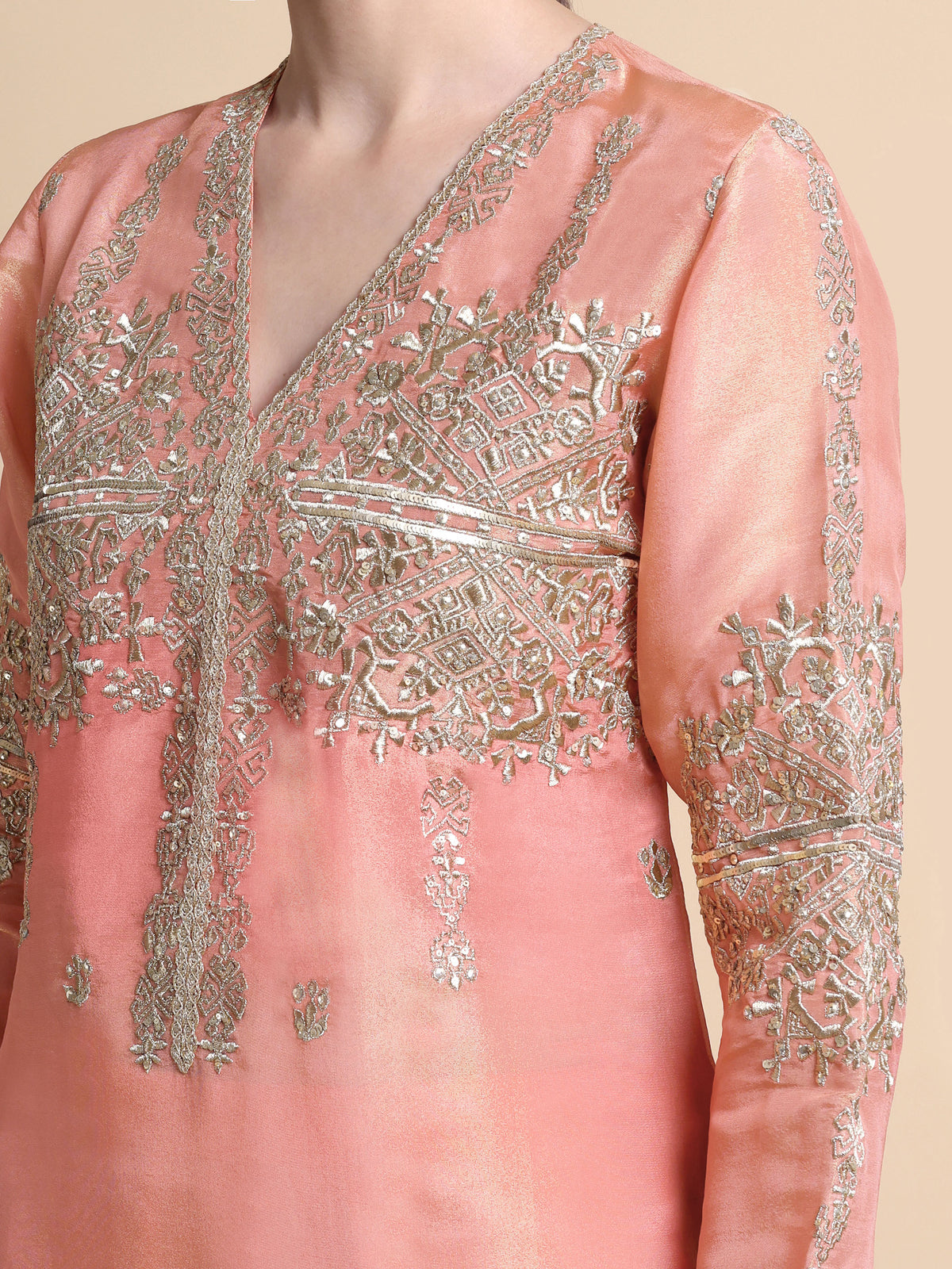 Pink embroidered garment with intricate silver detailing on a beige background