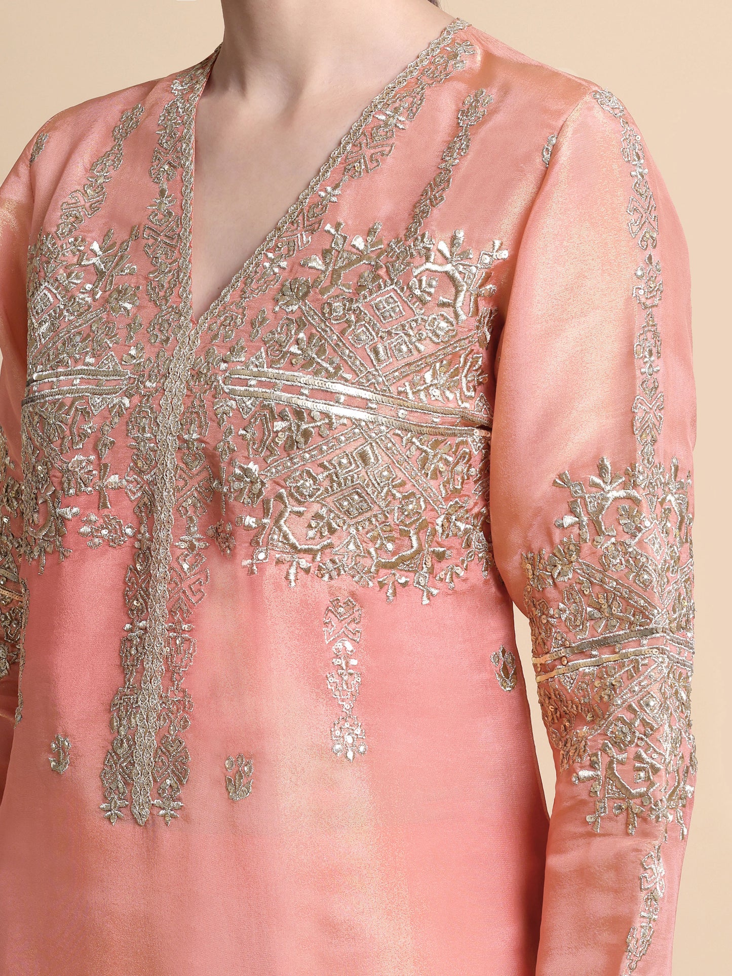 Pink embroidered garment with intricate silver detailing on a beige background
