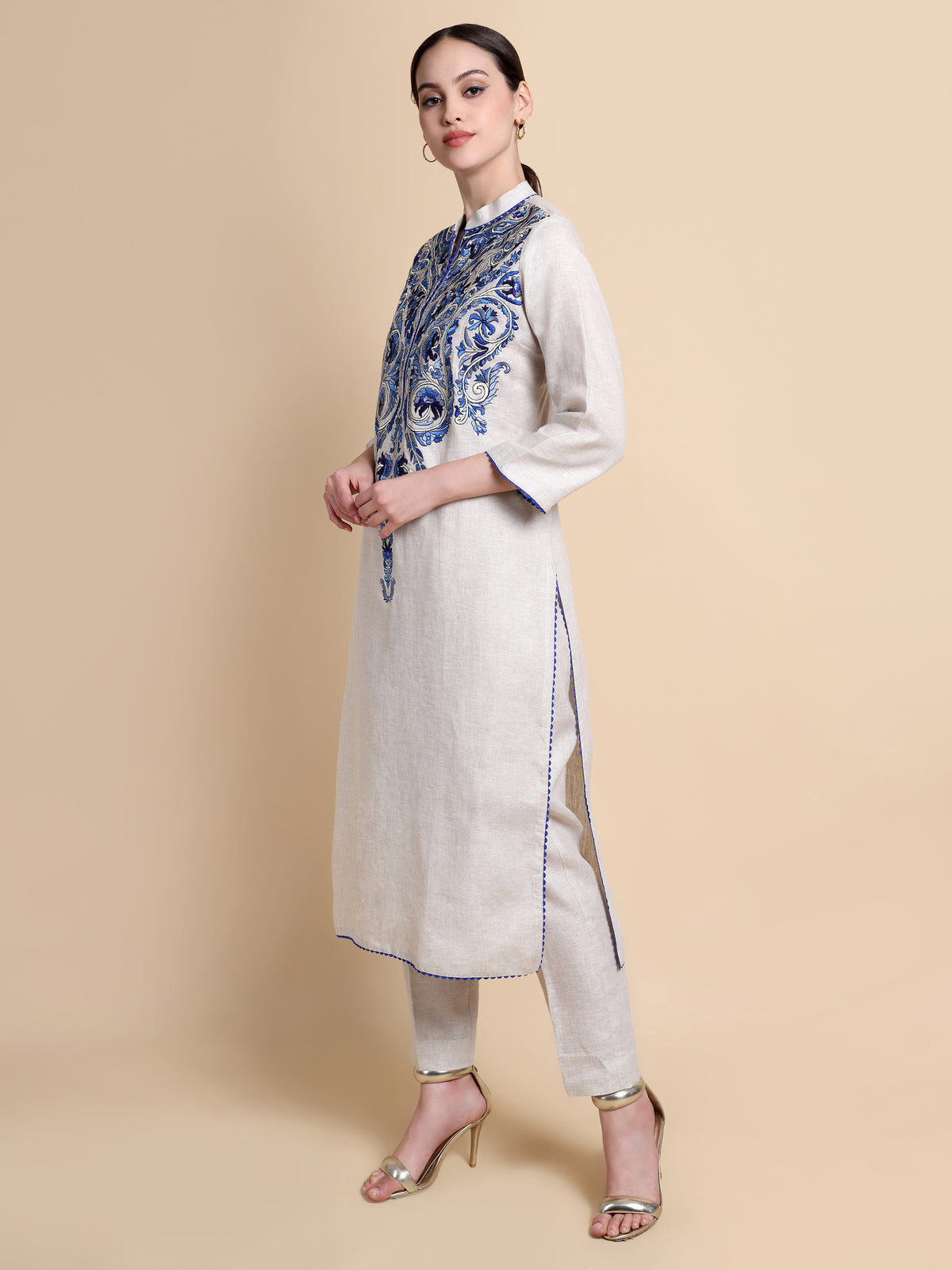 Woman wearing a white kurta with blue patterns and a beige background