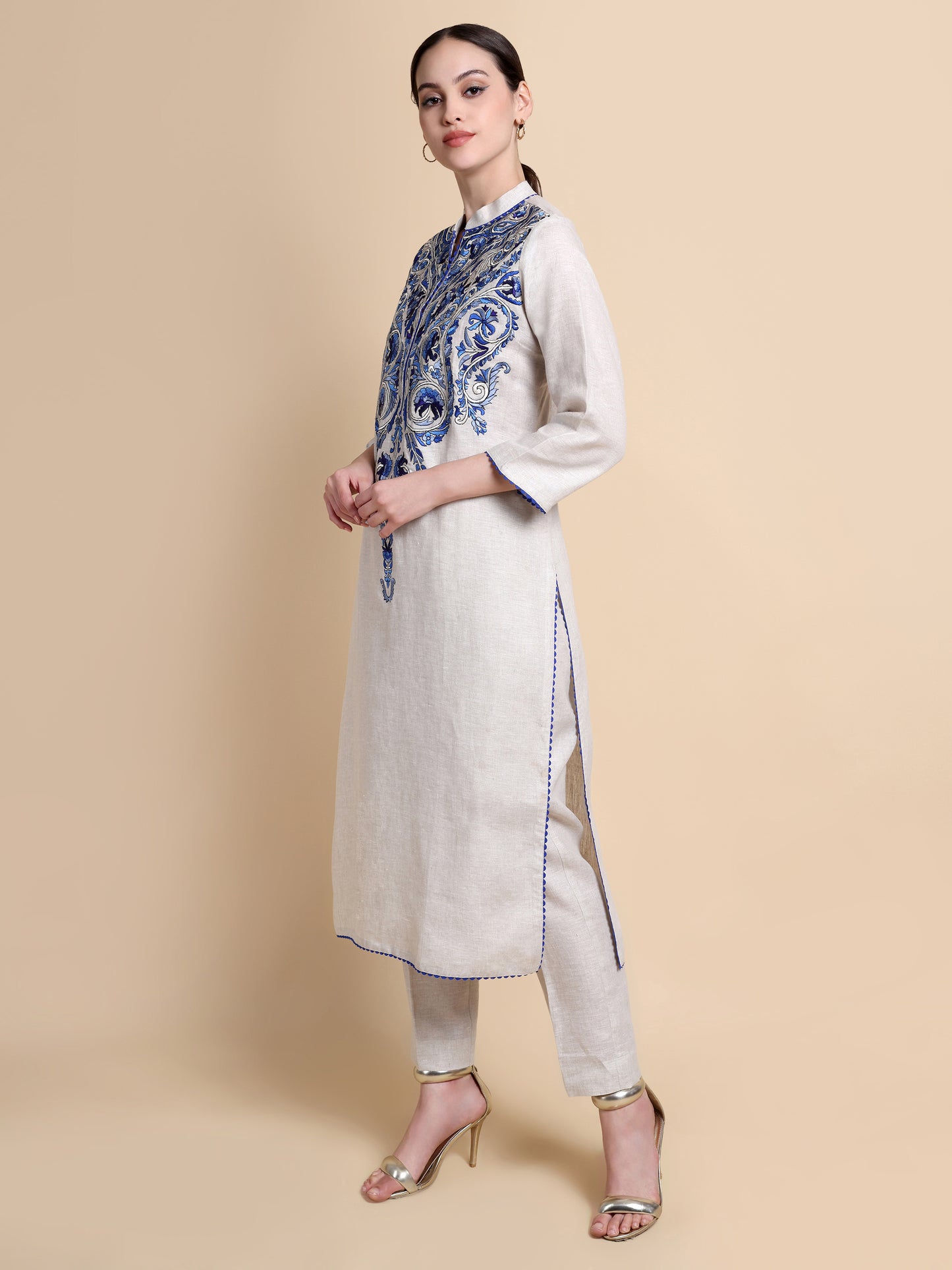 Woman wearing a white kurta with blue patterns and a beige background