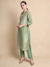 Woman wearing a green kurta with floral embroidery on a beige background