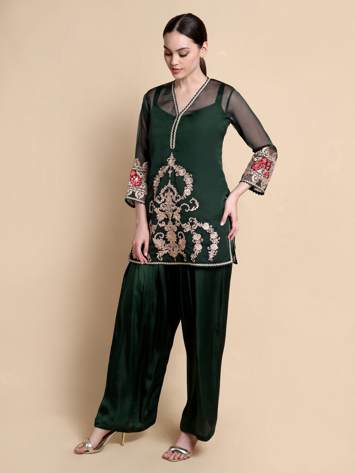 Woman wearing a dark green embroidered outfit on a beige background