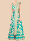 Teal embroidered traditional outfit with gold details on a beige background