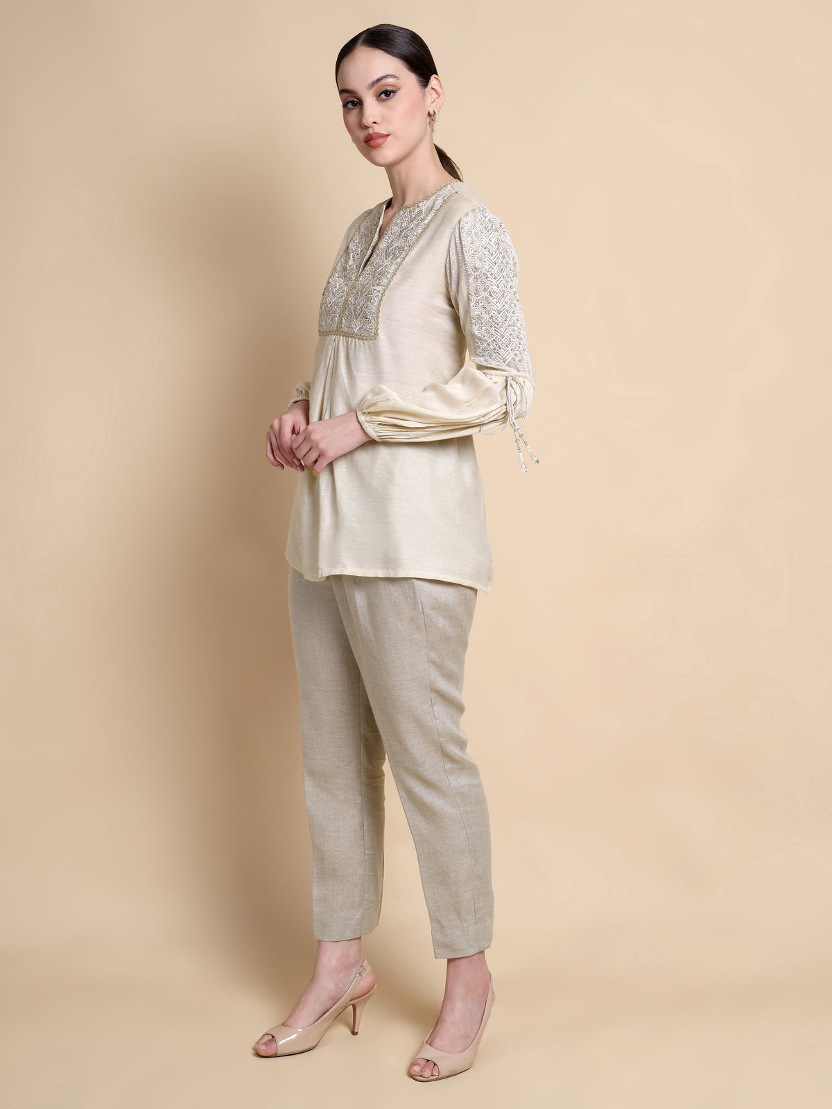 Woman wearing a beige outfit with floral patterns on a beige background