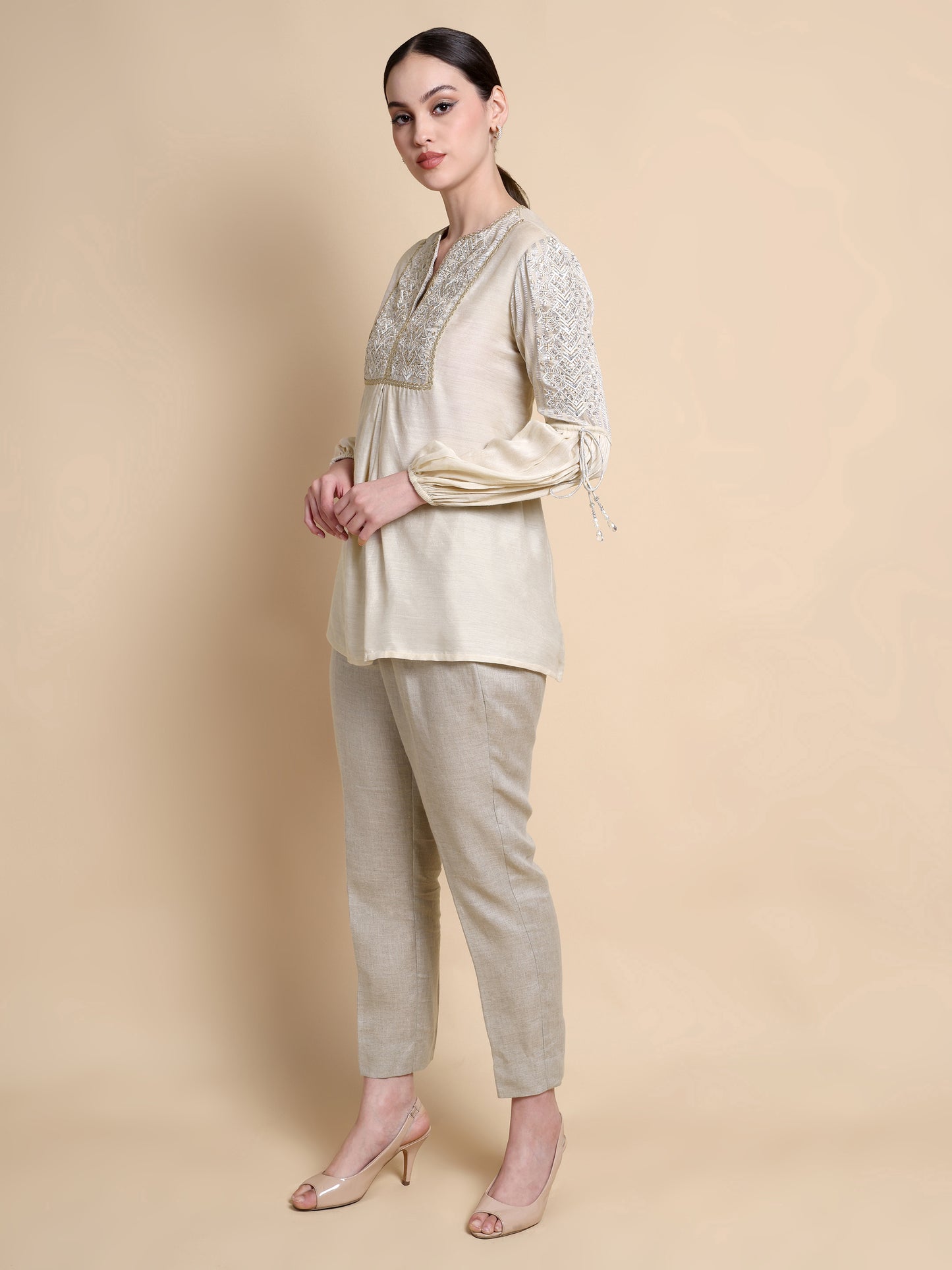 Woman wearing a beige outfit with floral patterns on a beige background