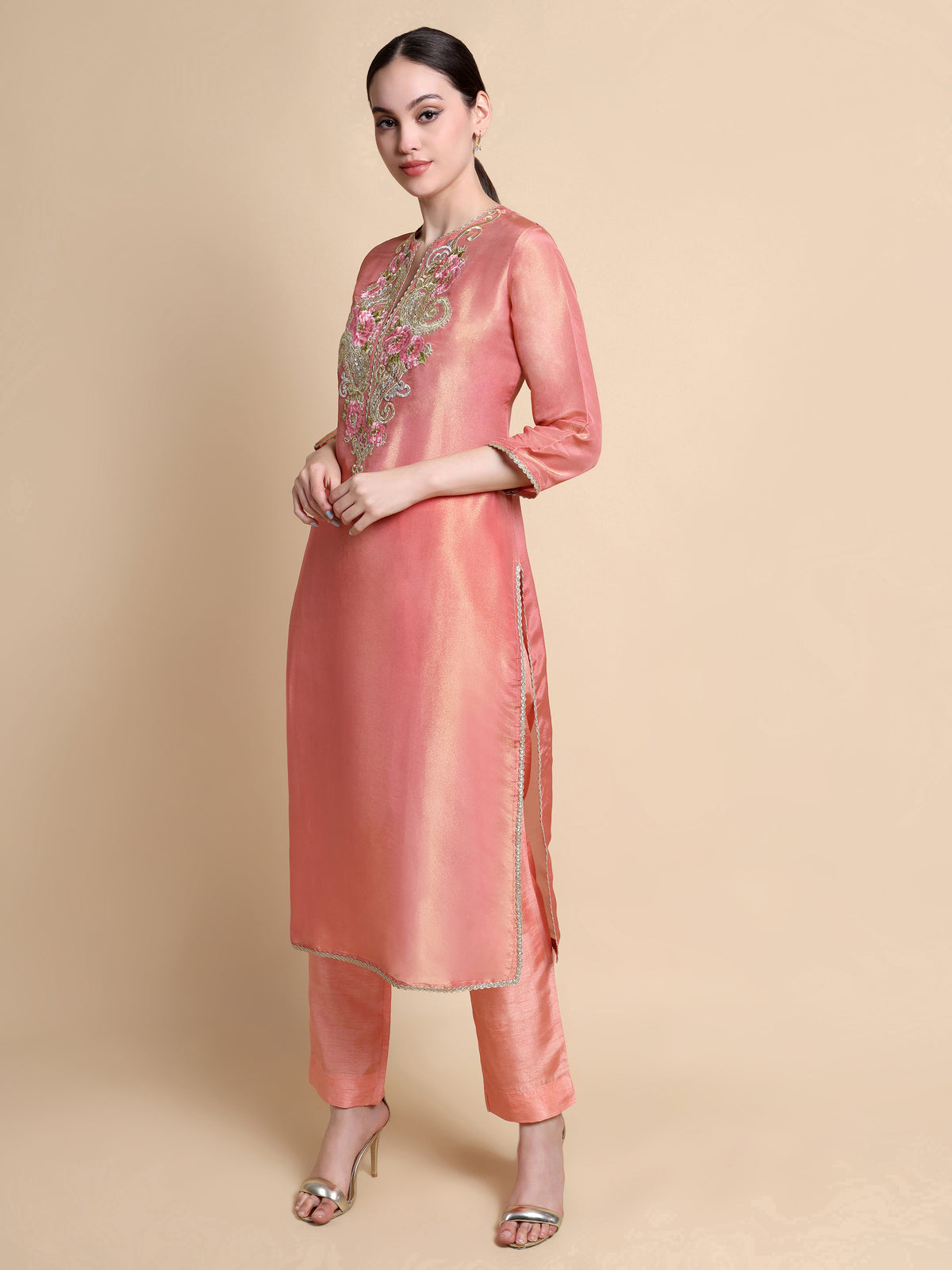 Woman wearing a peach kurta with embroidery on a beige background