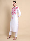 Woman wearing a white kurta with pink embroidery on a beige background