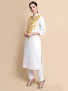 Woman wearing a white kurta with yellow embroidery on a beige background