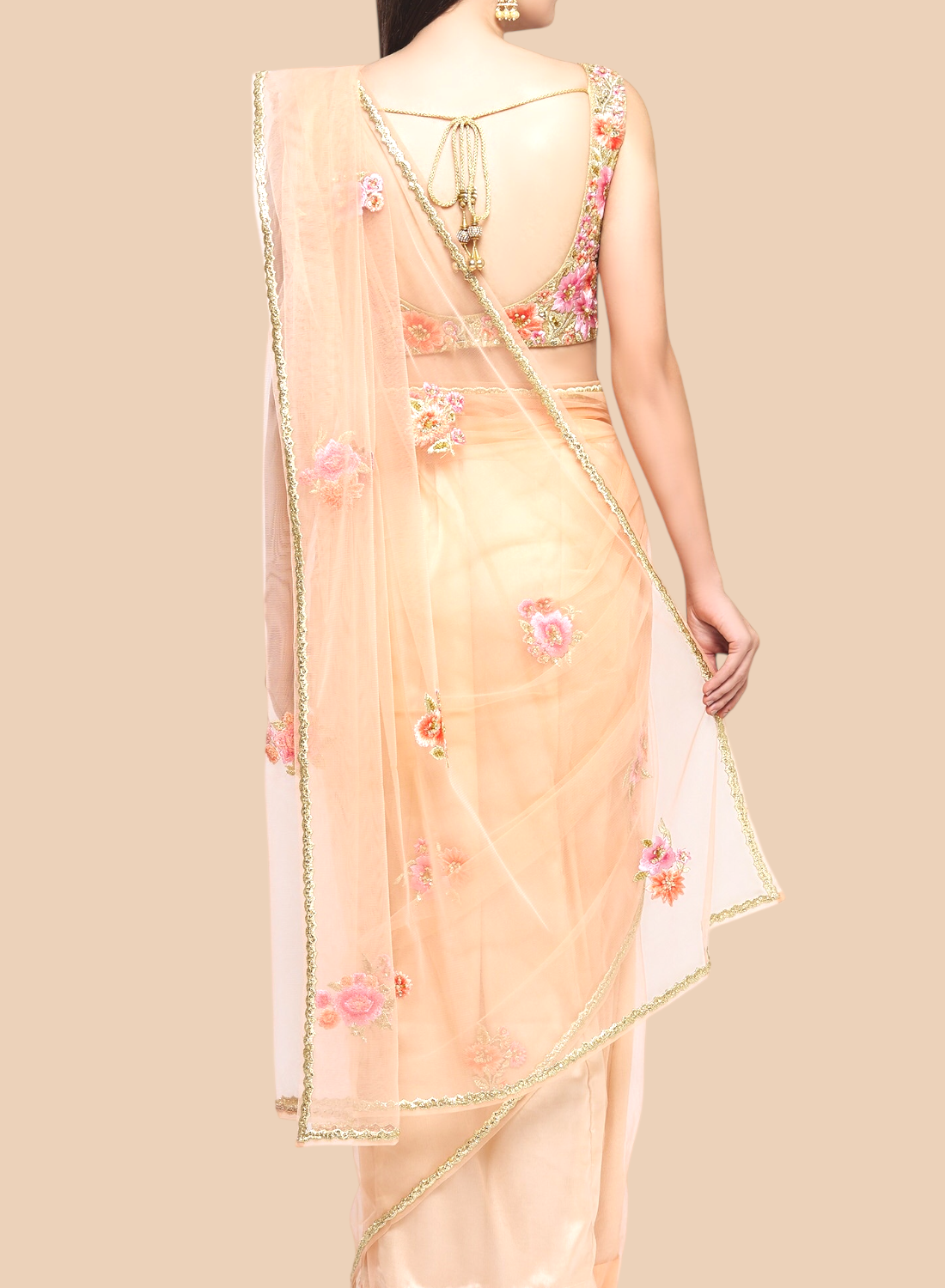 Luxurious peach net sari featuring floral embroidery, complemented by a sleeveless brocade blouse and unstitched petticoat.  