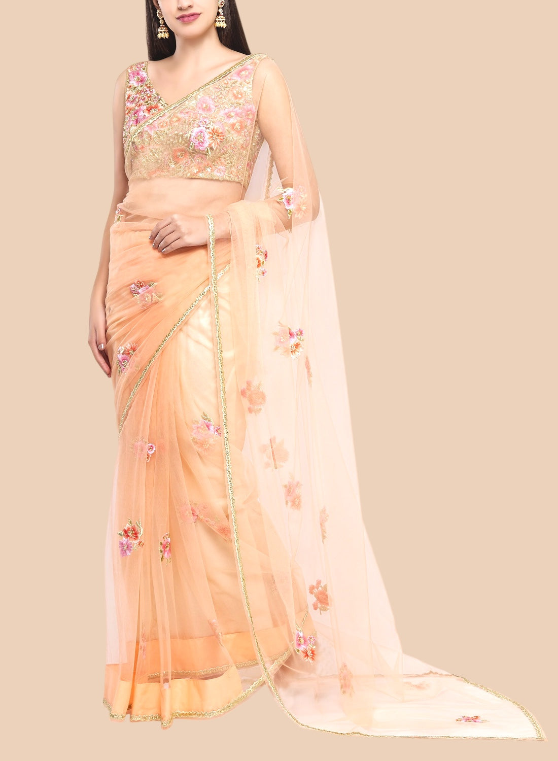 Luxurious peach net sari featuring floral embroidery, complemented by a sleeveless brocade blouse and unstitched petticoat.  