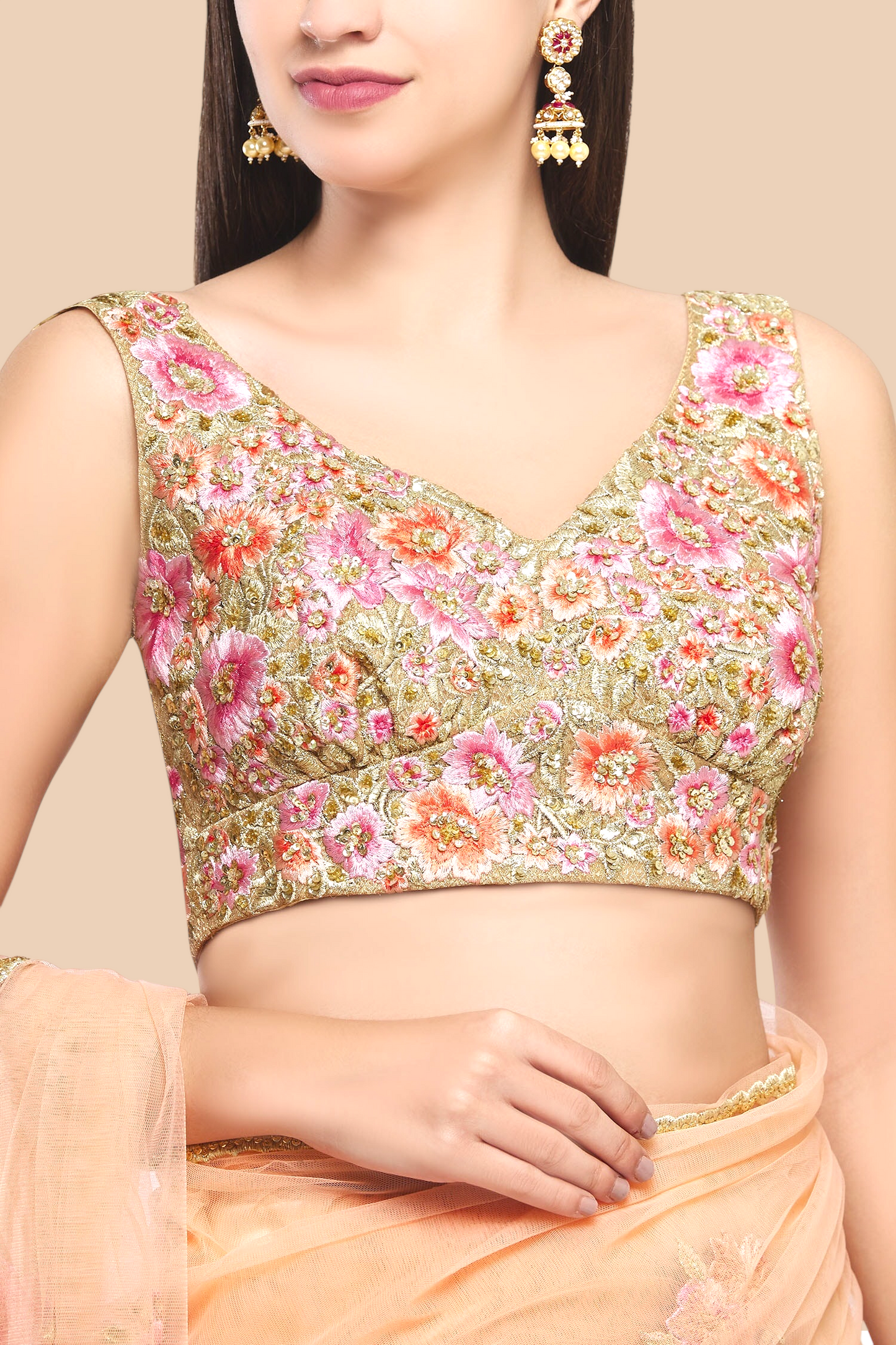 Luxurious peach net sari featuring floral embroidery, complemented by a sleeveless brocade blouse and unstitched petticoat.  