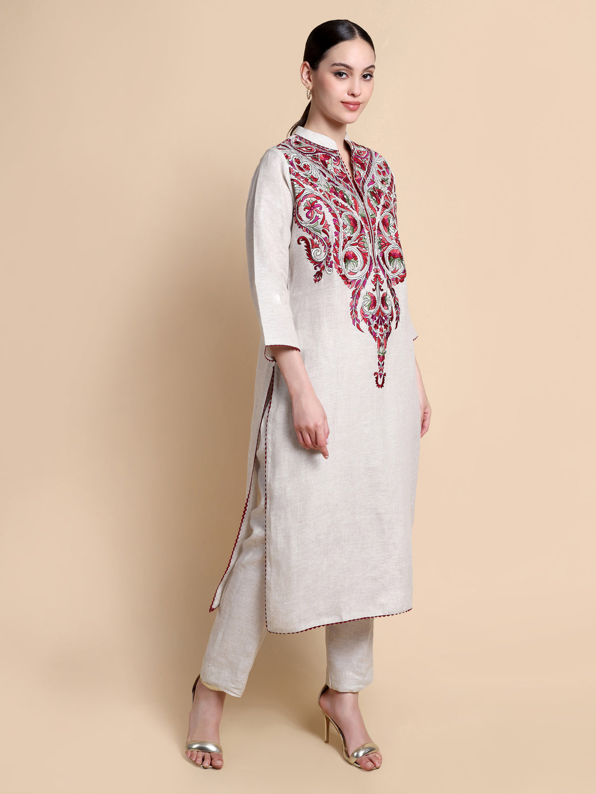 Woman wearing a white kurta with red embroidery on a beige background