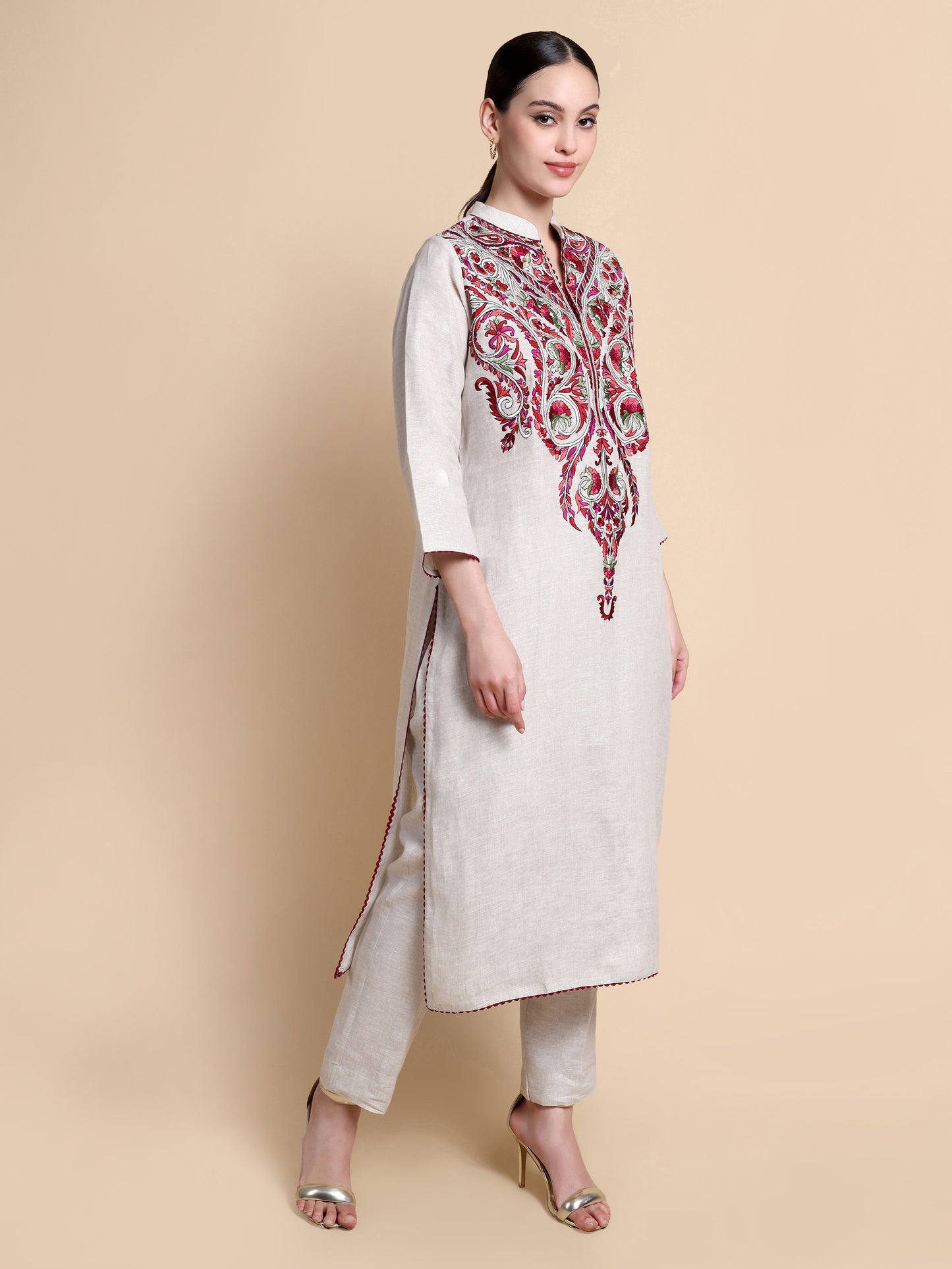 Woman wearing a white kurta with red embroidery on a beige background