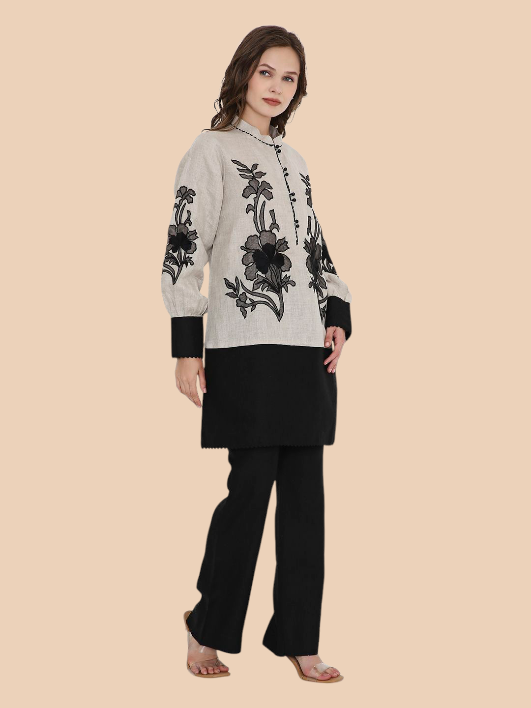 Woman wearing a black and white floral embroidered kurta with black pants on a beige background