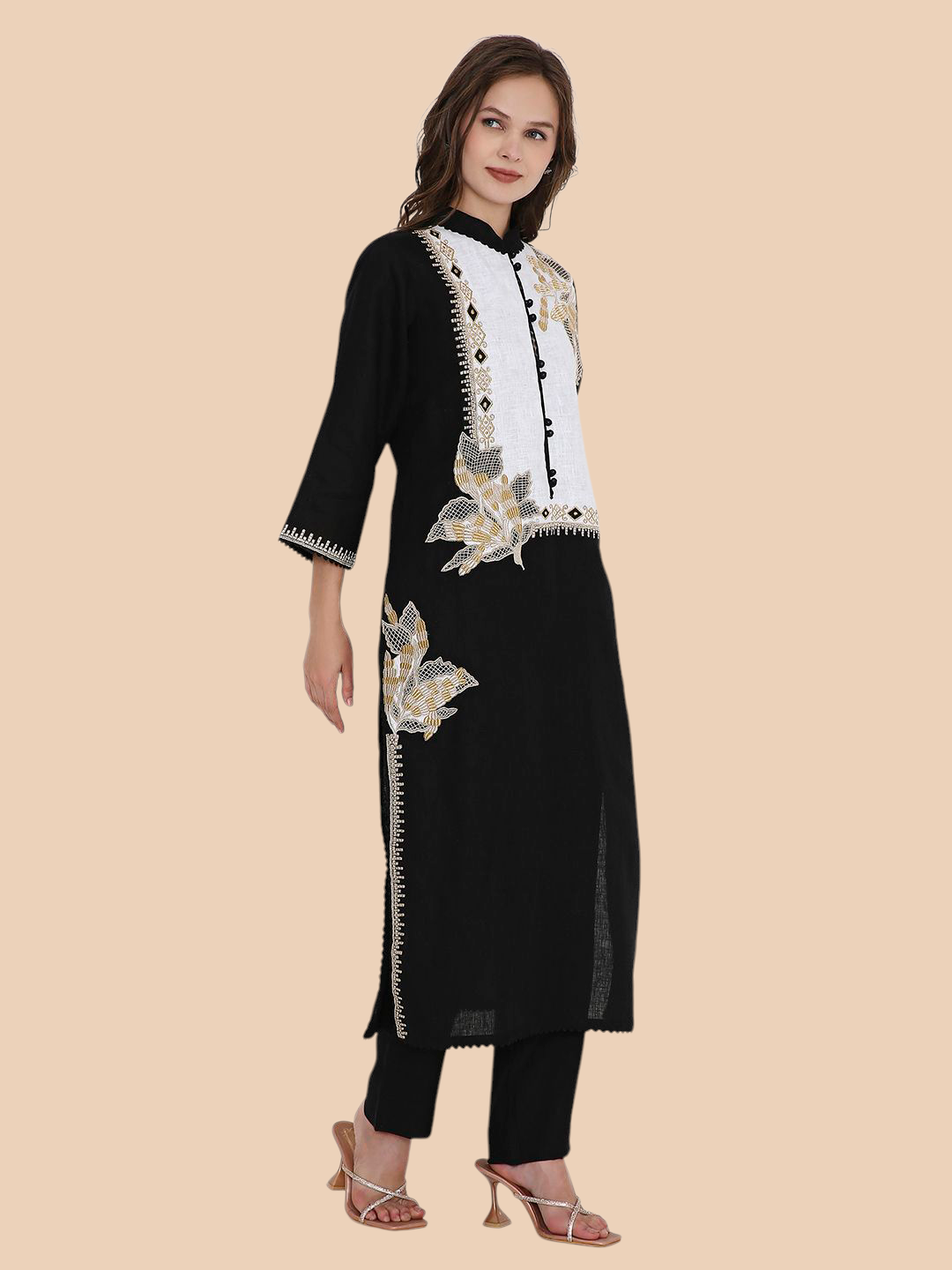Woman wearing a black and white embroidered kurta with black pants on a beige background