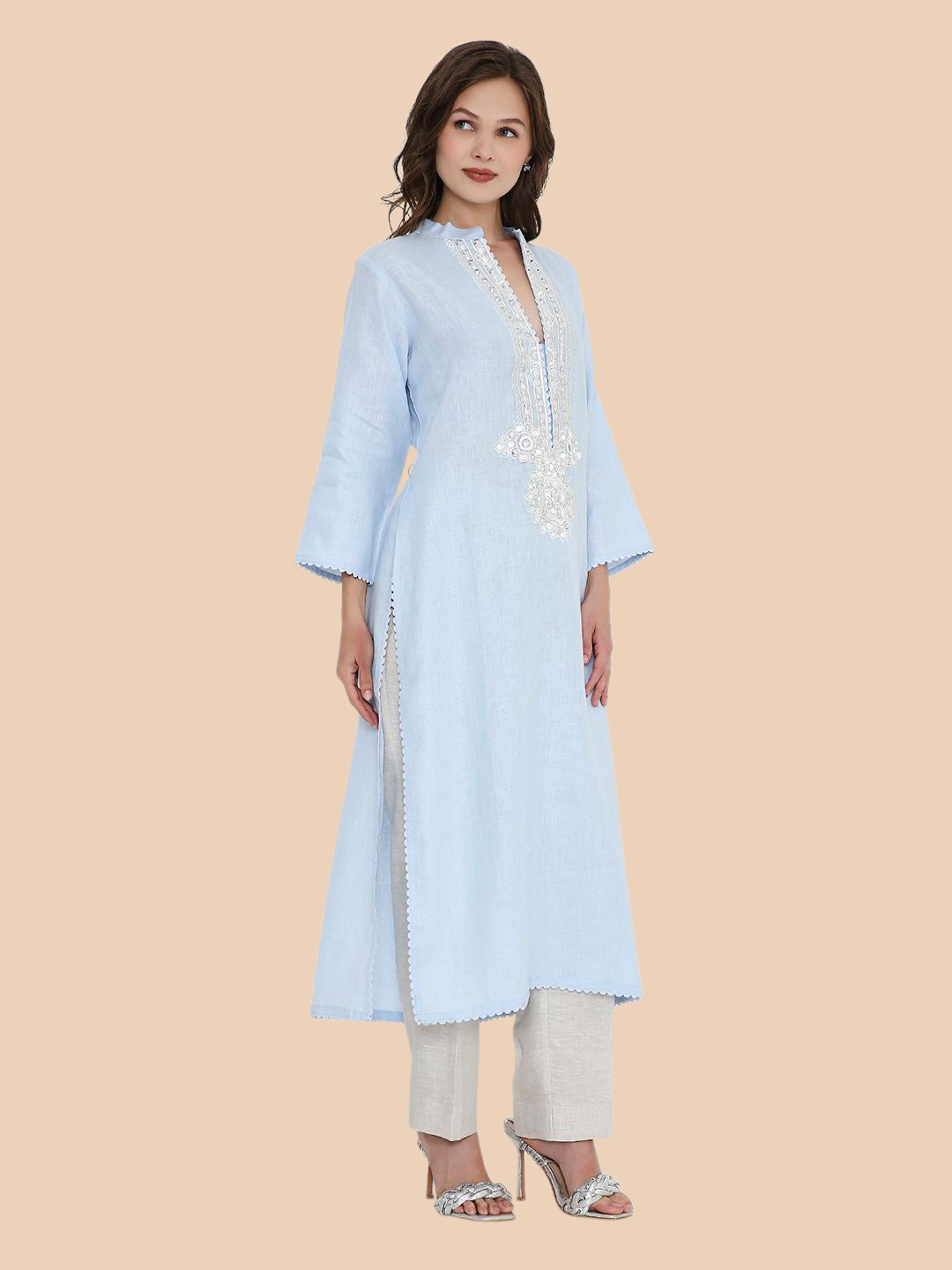 Woman wearing a light blue kurta with white embroidery on a beige background