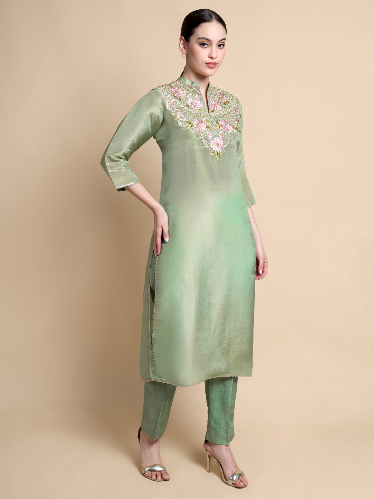 Woman wearing a light green kurta with floral embroidery on a beige background